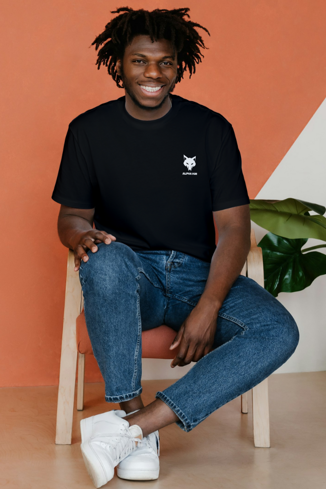 Smiling man wearing alpha hue unisex oversized graphic t-shirt in black with small logo sitting on chair