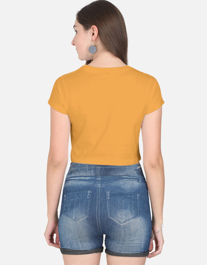 Back view of woman wearing an orange cute graphic crop top for women paired with denim shorts